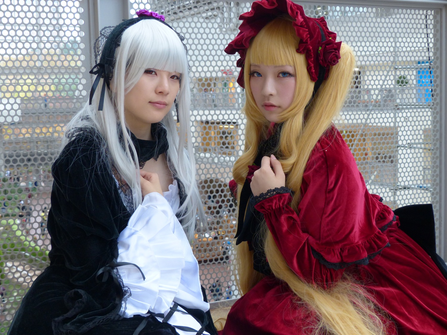 2girls bangs blonde_hair blue_eyes bonnet chain-link_fence dress fence flower frills hime_cut lips lolita_fashion long_hair long_sleeves looking_at_viewer multiple_cosplay multiple_girls photo realistic red_eyes tagme