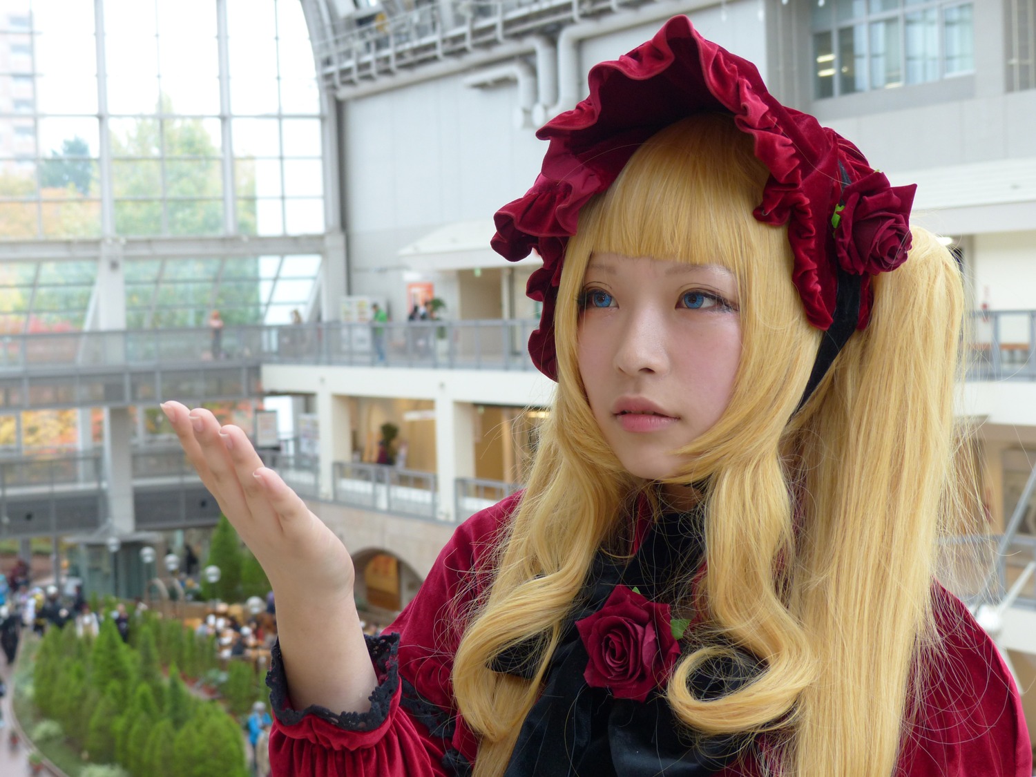 1girl bangs blonde_hair blue_eyes blurry bonnet building city day depth_of_field flower lips long_hair red_flower red_rose rose shinku solo