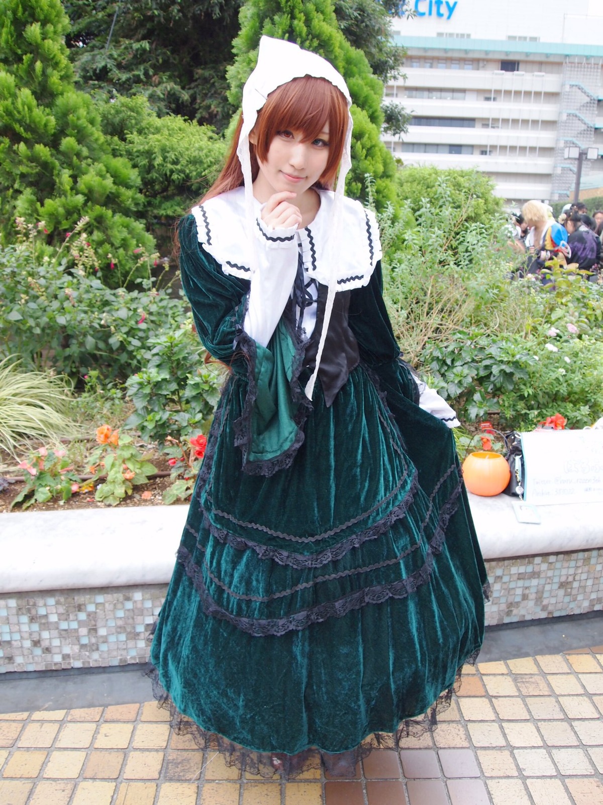 brown_hair chain-link_fence dress fence flower green_dress long_hair long_sleeves looking_at_viewer multiple_girls outdoors pavement smile solo standing suiseiseki tile_floor tiles tree