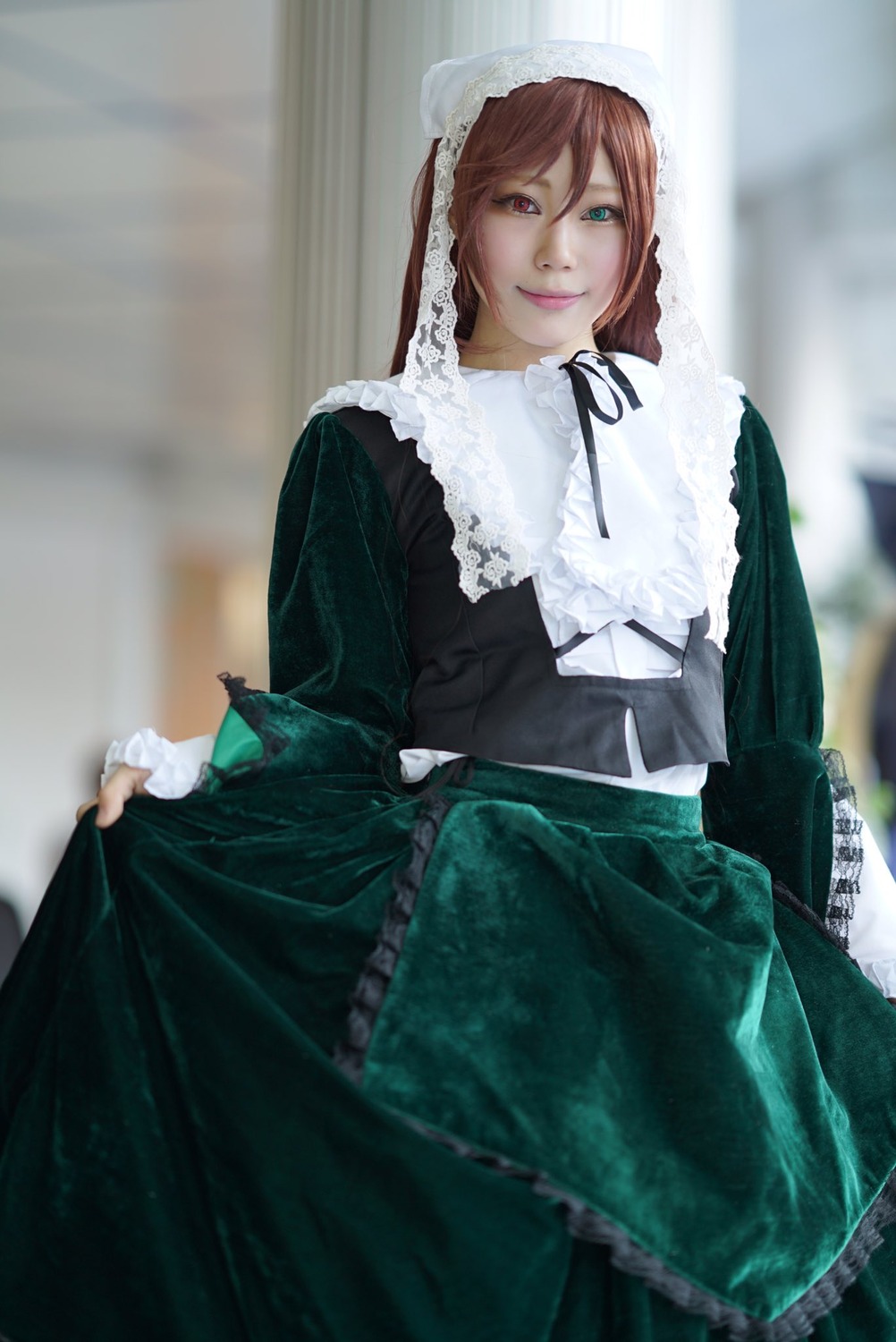 1girl blurry blurry_background brown_hair depth_of_field dress frills green_dress green_eyes heterochromia lips long_hair long_sleeves looking_at_viewer red_eyes ribbon skirt_hold smile solo suiseiseki