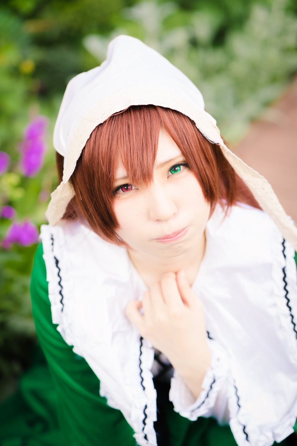 1girl bangs blurry blurry_background blurry_foreground bonnet brown_hair closed_mouth depth_of_field flower green_eyes head_scarf heterochromia lips long_sleeves looking_at_viewer motion_blur photo red_eyes smile solo souseiseki suiseiseki