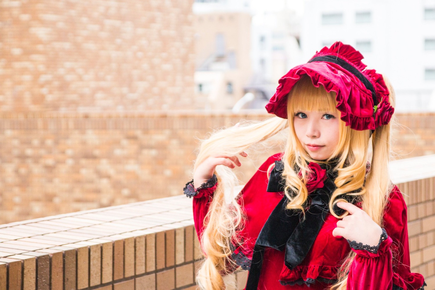 1girl bangs blonde_hair blue_eyes blurry blurry_background bonnet building depth_of_field dress flower lips lolita_fashion long_hair long_sleeves looking_at_viewer outdoors red_dress shinku solo upper_body