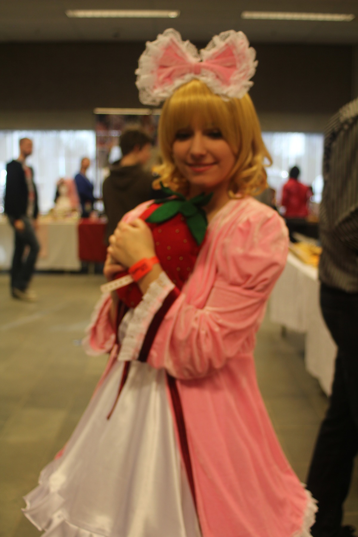 1girl blonde_hair blurry blurry_background blurry_foreground bow depth_of_field dress figure hinaichigo photo pink_dress smile solo solo_focus