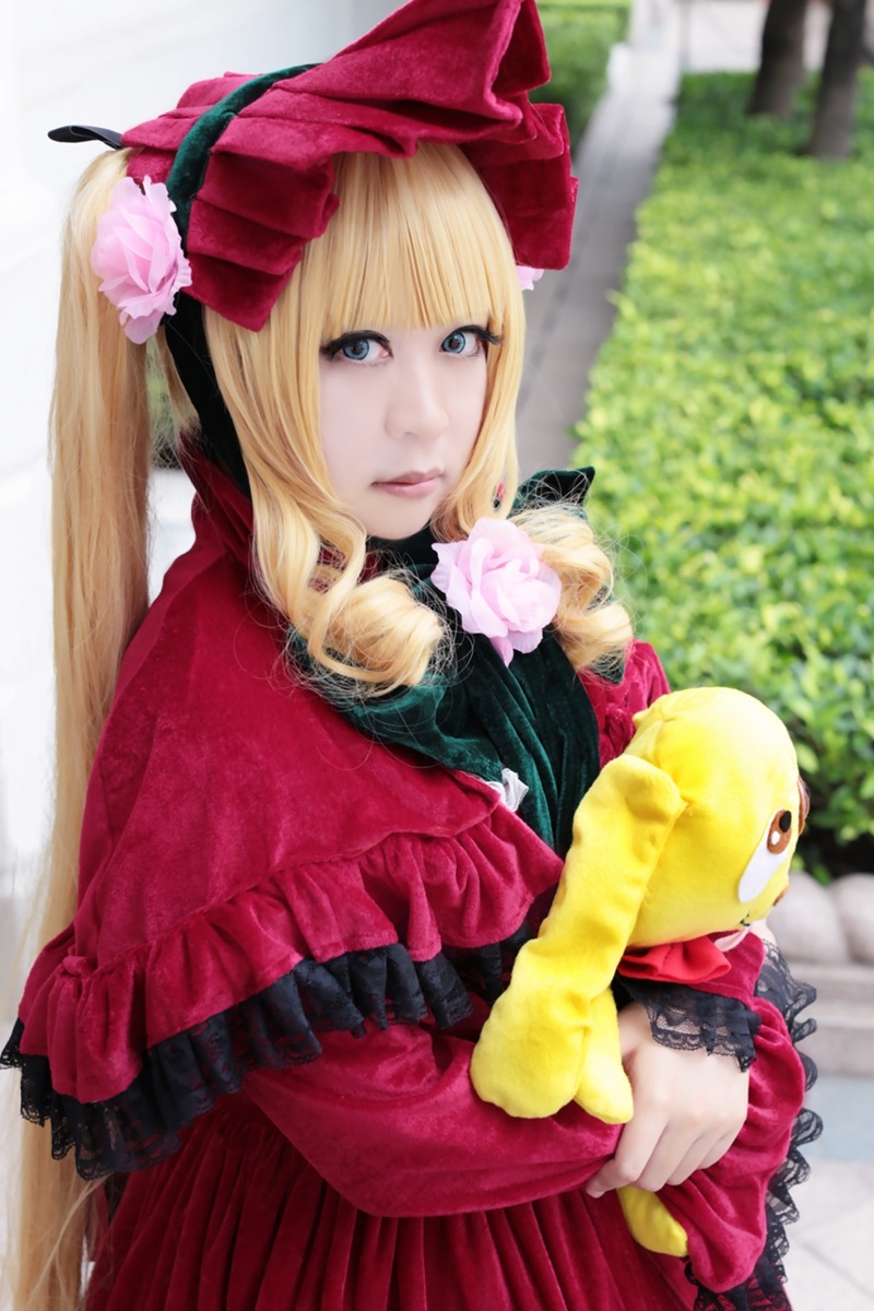 1girl bangs blonde_hair blue_eyes blurry blurry_background bonnet depth_of_field dress flower frills lips long_hair looking_at_viewer outdoors photo red_dress rose shinku solo