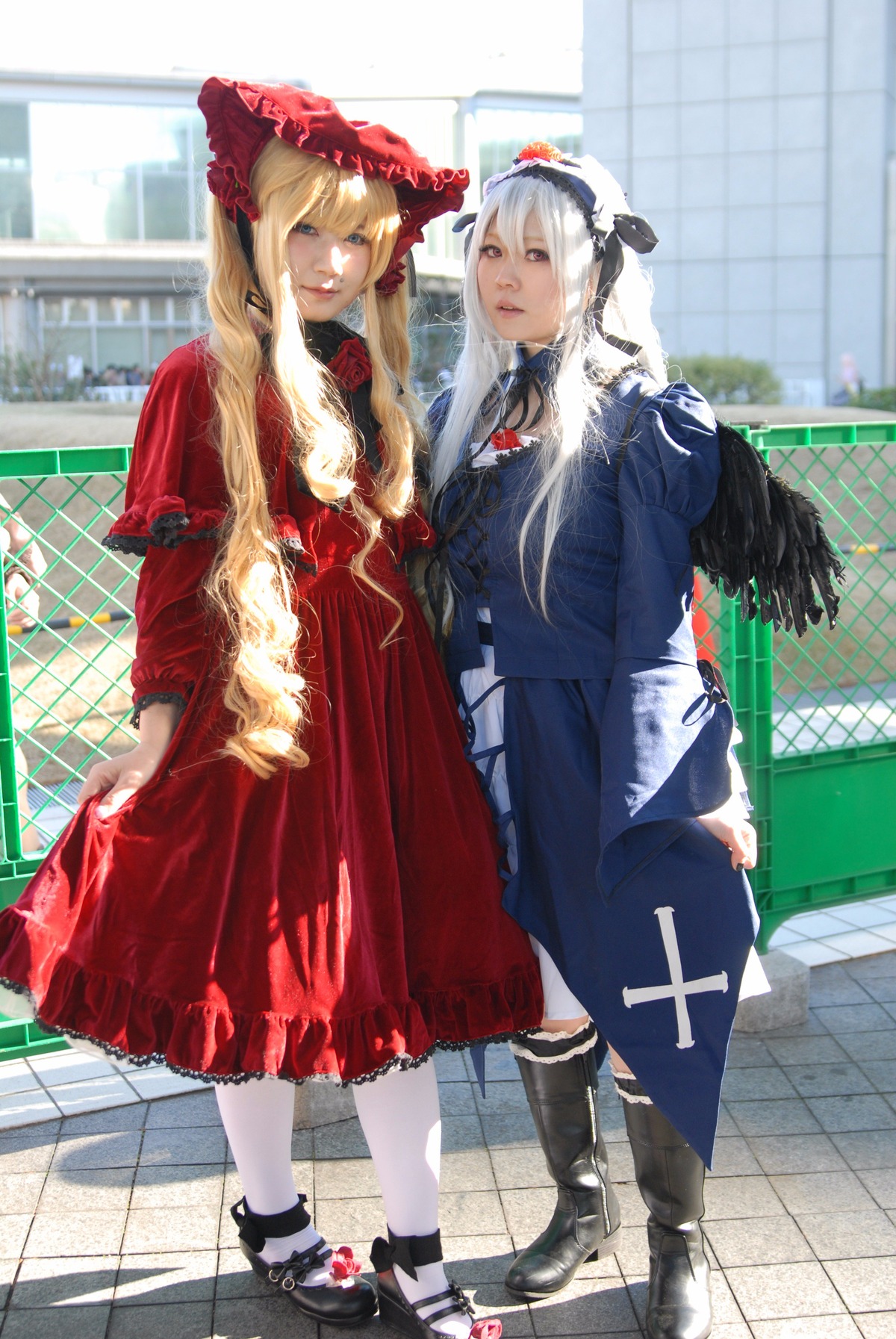 2girls black_footwear blonde_hair blurry bonnet boots chain-link_fence depth_of_field dress fence frills long_hair long_sleeves looking_at_viewer multiple_cosplay multiple_girls pavement shinku silver_hair standing tagme tile_floor tiles white_legwear